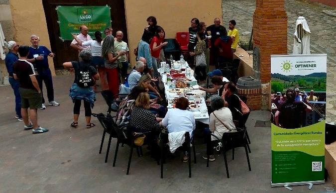 Desayuno 1 los participantes algunos sentados, otros de pié alrededor de una mesa alargada comparten desayuno y conversación animada
